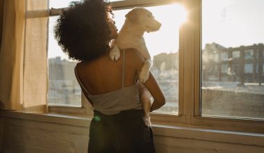 black woman holding dog near window