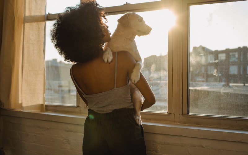 black woman holding dog near window